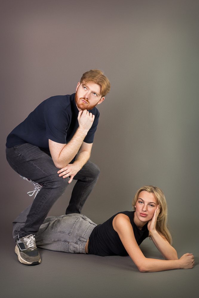 Awkward couples portrait session pose against a studio backdrop