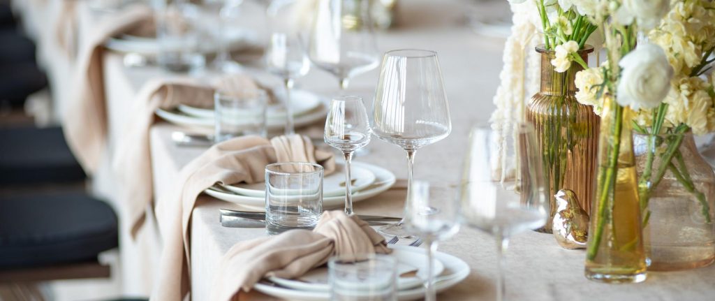 Elegantly set banquet table with neutral linens and glassware