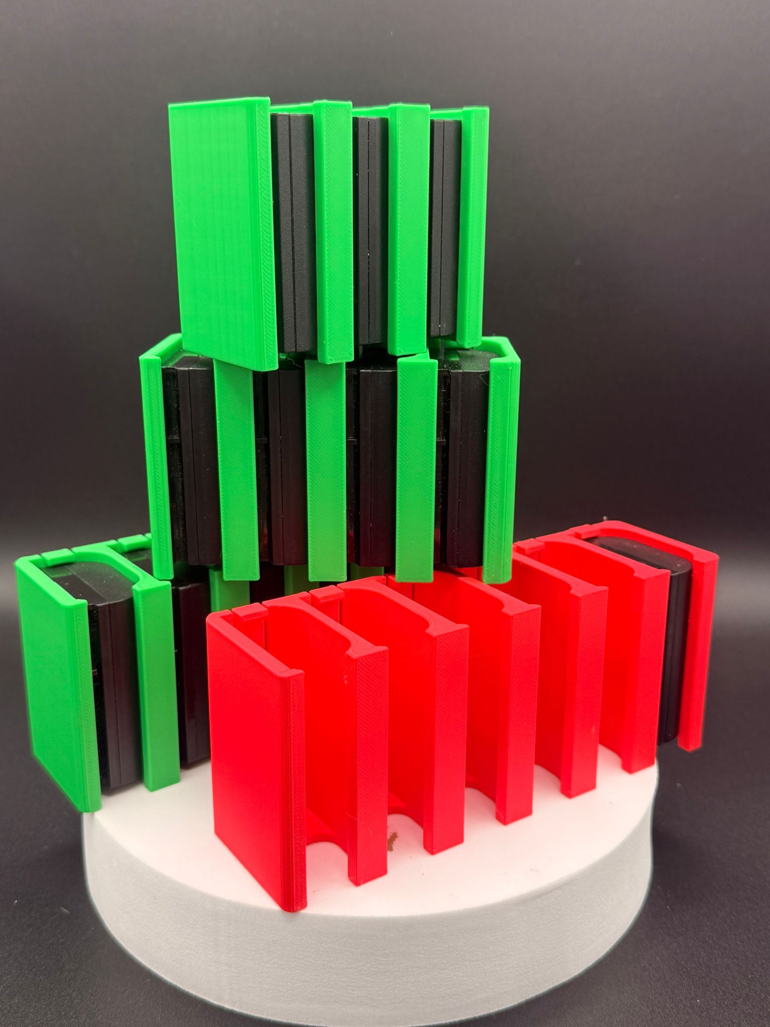 Stack of 3D-printed Canon LP-E6 battery holders in green and red, made by Home Forge Studio