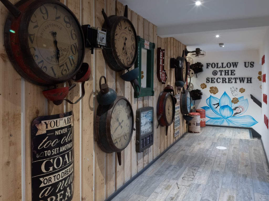 Secret Warehouse Kirkdale wall of vintage clocks and cameras with Follow Us mural